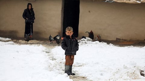 An Afghan boy stands on snow-covered ground in Kabul