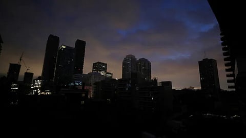 Blacked-out residential buildings are silhouetted against the sky during a short electrical power outage in midtown Toronto on Jan. 6, 2023