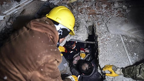 Emergency workers and medics rescue a woman out of the debris of a collapsed building in Elbistan, Kahramanmaras, in southern Turkey