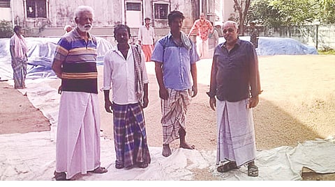 Farmers with piled up paddy at Puliyanchery village near Kumbakonam