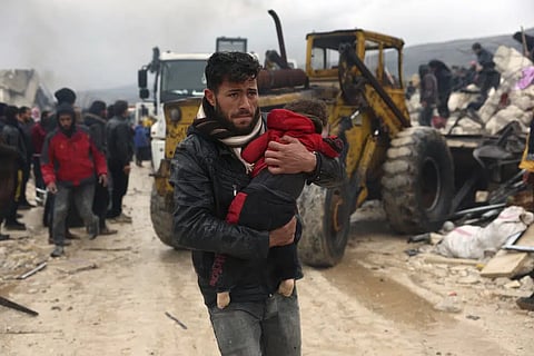 Man carrying his child in Syria's Idlib region