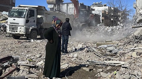 Parents of Taha Erdem, mother Zeliha Erdem, left, and father Ali Erdem stand next to the debris from the building where Tahan was trapped after the earthquake of Feb. 6, in Adiyaman, Turkey.