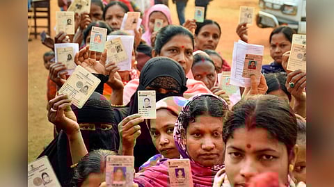 Voters show their identification cards as they wait in queues to cast their votes