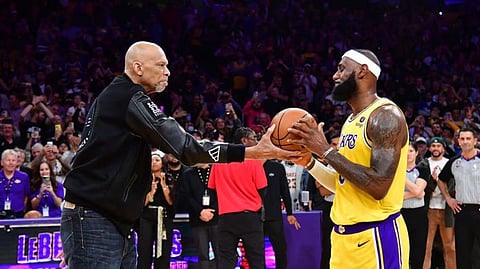 Former Los Angeles Lakers player Kareem Abdul-Jabbar hands the game ball to forward LeBron James