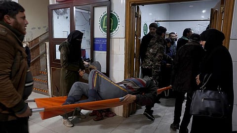 People carry a man injured in an earthquake into the al-Rahma Hospital in the town of Darkush