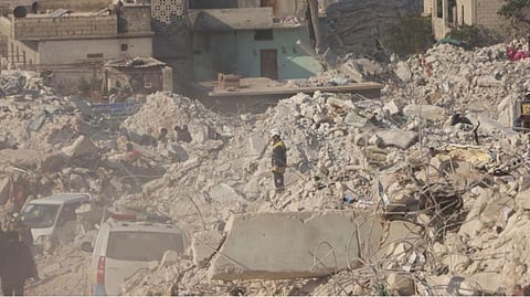 A White Helmet volunteer stands among rubble, in the aftermath of a deadly earthquake, in Harem