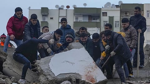 Men search for people among the debris in a destroyed building in Adana, Turkey