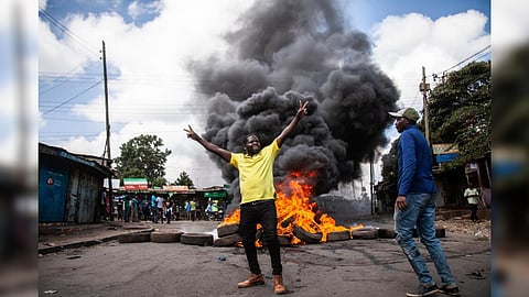 Protesters react next to a burning barricade during a mass rally called by the opposition leader Raila Odinga over the high cost of living, in Kibera Slum, Nairobi, Kenya