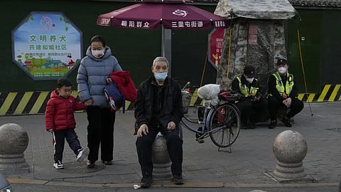 Residents wait to cross a road near members of the Chaoyang militia on duty in Beijing