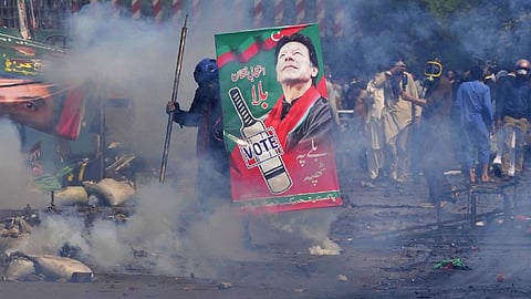 Supporters of former Prime Minister Imran Khan take cover after riot police officers fire tear gas to disperse them during clashes, in Lahore, Pakistan, March 15, 2023