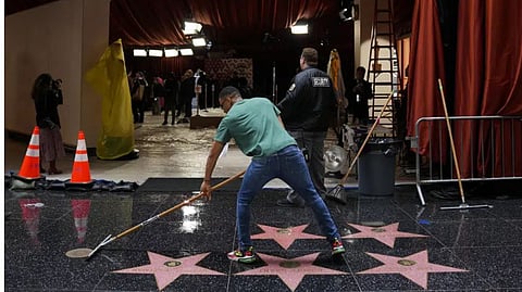 A worker sweeps away rainwater from the Walk of Fame during preparations for Sunday's 95th Academy Awards.
