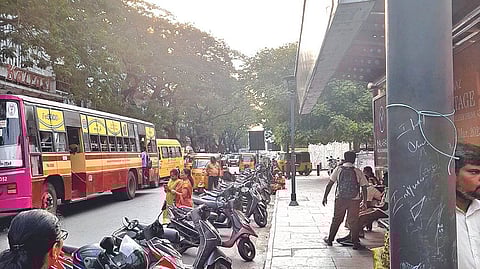 An MTC service stopped in the middle of the road as two-wheelers occupy space near the bus stand in Pondy Bazaar