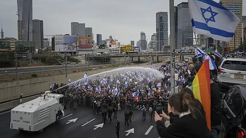Israeli police use a water cannon to disperse Israelis blocking the freeway during a protest