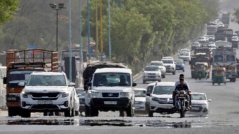 Traffic moves on a road in a heat haze during hot weather on the outskirts of Ahmedabad