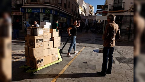A worker pulls a cart with boxes in Ronda
