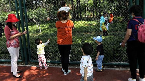 Children play next to adults at a park in Beijing, China June 1, 2021.