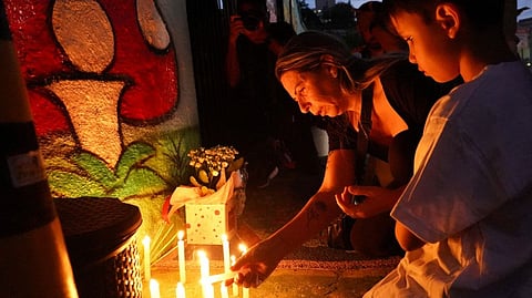 A woman lights a candle during a tribute to victims