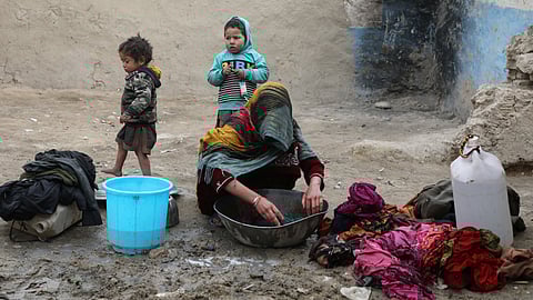 An internally displaced Afghan woman washes clothes outside her shelter on the outskirts of Kabul