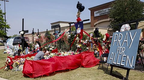 People place flowers and pay their respects at a memorial for victims of the Allen Premium Outlets mass shooting, Tuesday, May 9, 2023, in Allen, Texas.