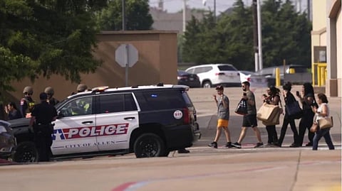 People raise their hands as they leave a shopping center following reports of a shooting Saturday in Allen, Texas.
