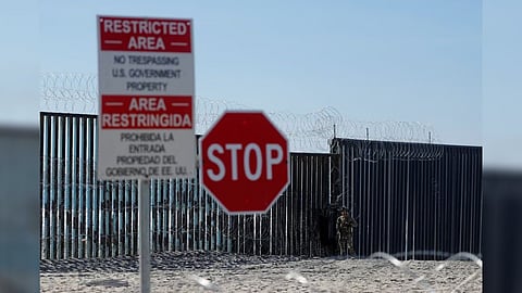 An armed U.S. Customs and Border Patrol agent stands watch at the border fence next the the beach in Tijuana, at the Border State Park in San Diego, California, U.S.