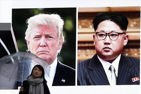 A woman walks by a huge screen showing US President Donald Trump and North Korean leader Kim Jong Un