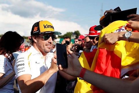 McLaren's Fernando Alonso signs his autograph for fans