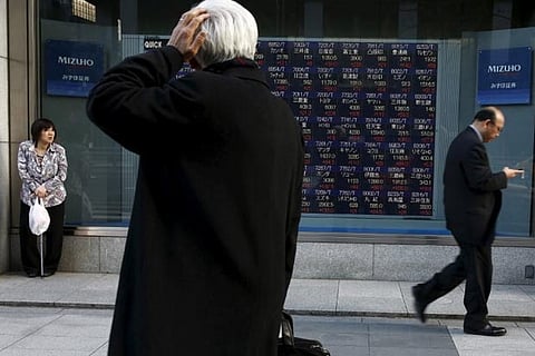 A man looks at an electronic board showing market indices outside a brokerage in Tokyo, Japan