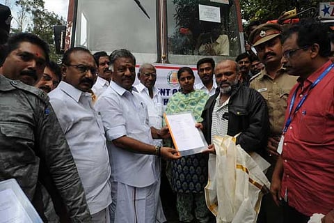 OPS handing over relief material to Revenue officials of neighbouring Kerala at Idukki check post