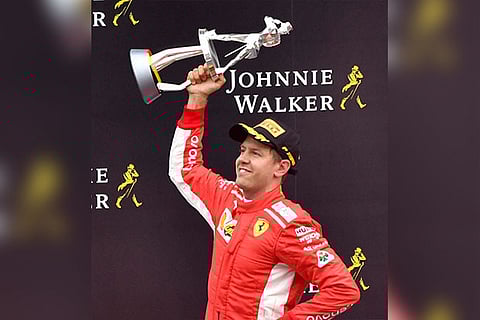 Ferrari driver Sebastian Vettel of Germany jubilates with his trophy on the podium