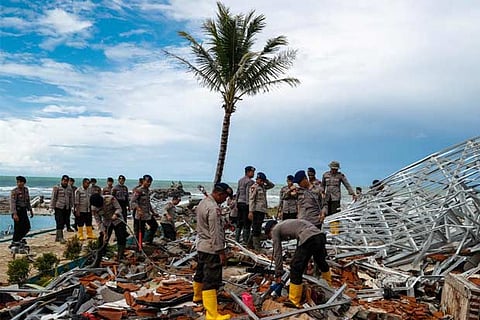 Police officers search for victims among rubble of a  tsunami-hit beach front hotel