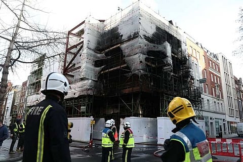 Firefighters look at the damaged caused by a fire at a construction site in central London