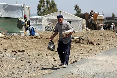 Internally displaced man holds a stack of bread near the Israeli-occupied Golan Heights