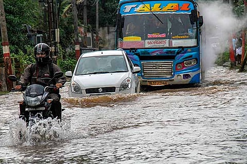 File photo of commuters wading across a waterlogged road in Kozhikode