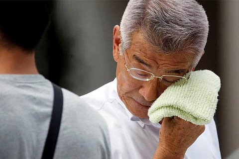A businessman wipes his face while walking on a street during a heatwave in Tokyo