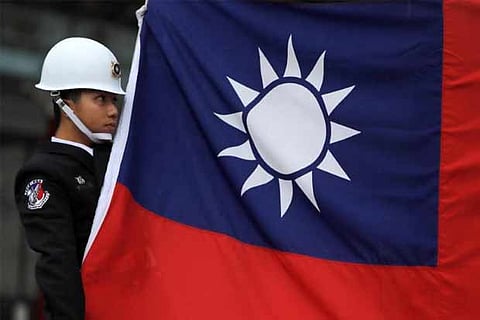 A military honour guard holds a Taiwanese national flag as he attending flag-raising ceremony