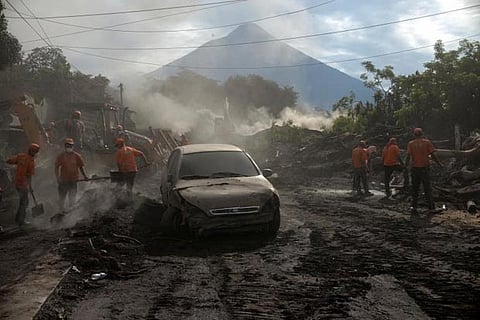 Workers remove ashes from a road at El Rodeo in Escuintla