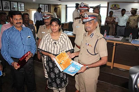 Police Commissioner AK Viswanathan handing over a guide on cyber security to workshop participants.