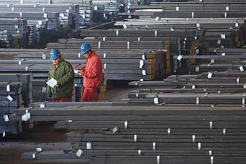 Workers check steel bars at a factory in Liaoning province, China