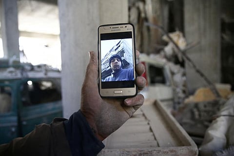 Abu Mohammad Alaya, 50, holds a mobile phone with his son Mohammad's picture on the screen