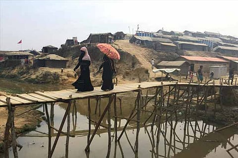 Women walk across a bamboo bridge in the Kutupalong camp for Rohingya refugees in southern Banglades