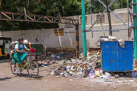 A school student pedals her way through a street filled with garbage in Chennai