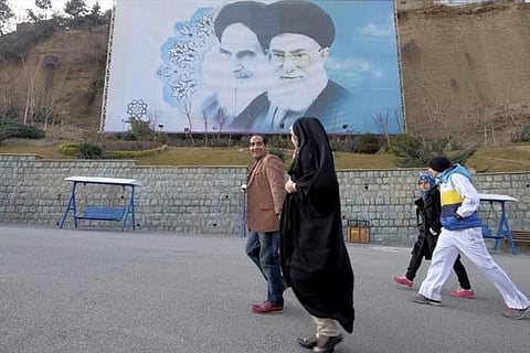 People walk past a large picture of Ayatollah Ruhollah Khomeini (L), and Ayatollah Ali Khamenei
