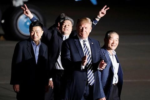 The three Americans formerly held hostage in North Korea gesture next to US Prez Trump