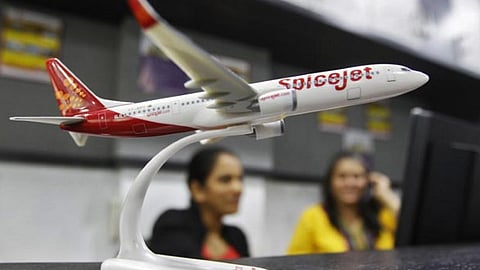 Employees work inside a travel agency office besides a model of a SpiceJet aircraft