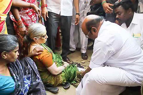Minister D Jayakumar gives first aid to the woman, who suffered an injury after a loudspeaker fell on her feet