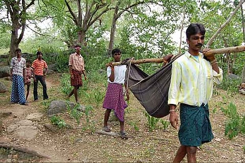 Tribal residents carrying a patient in a dolie on Jawadhu Hills