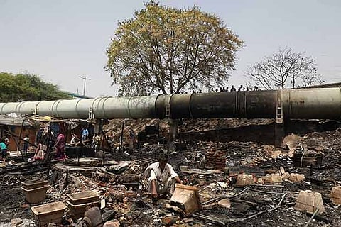 A man sits in the rubble of his burnt shack after a fire at a slum in New Delhi