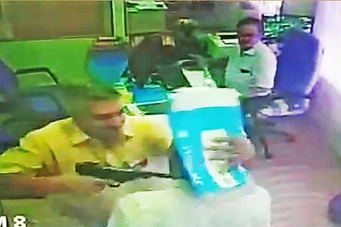 The CCTV video grab shows the man threatening a staffer of the bank at gunpoint in Coimbatore on Wednesday
