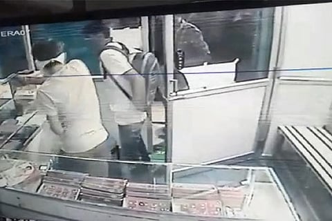 CCTV grab of a gang member pointing a gun at the shop owner